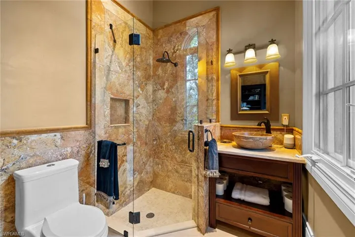 Frameless glass shower enclosure featuring natural stone tiling and a built-in niche