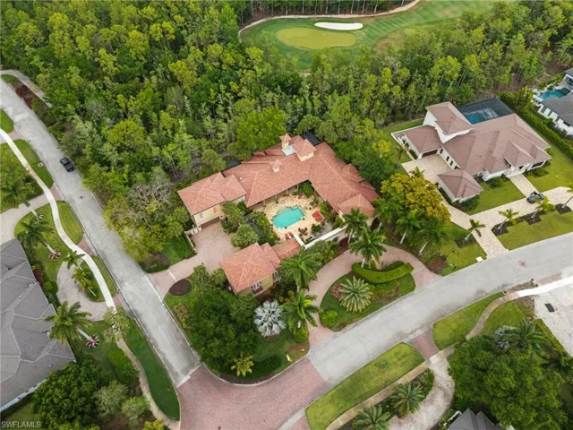 Mediterranean-style property featuring a central courtyard with a swimming pool, a red tile roof, and a meticulously landscaped circular driveway