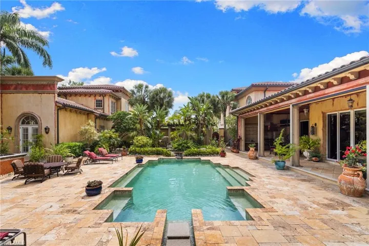 Courtyard-style pool area featuring a rectangular pool with integrated steps, surrounded by stone pavers