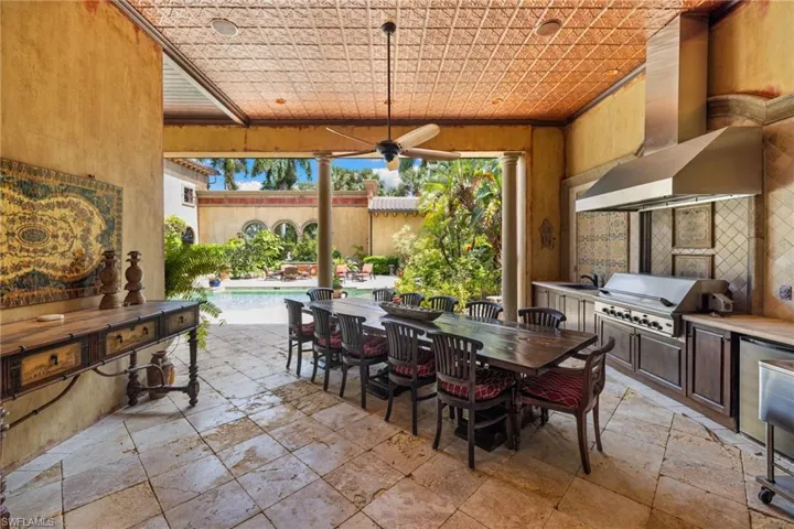 Covered outdoor living space featuring an integrated kitchen with a built-in grill and stainless steel hood