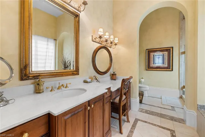 Double vanity with white countertop and integrated sink, gold-tone fixtures, and ornate framed mirrors