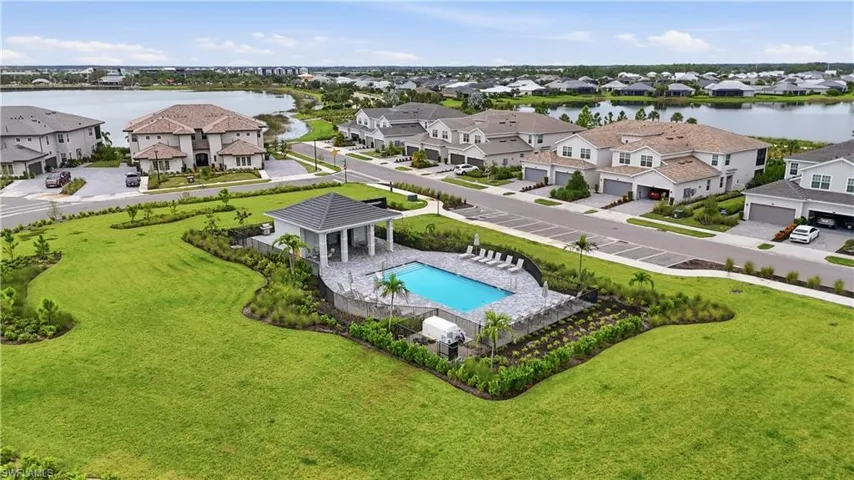 Community pool with shaded cabana, surrounded by lush landscaping and expansive green spaces