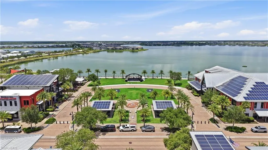 Expansive waterfront community featuring a central green space, mature palm trees, and solar-paneled rooftops