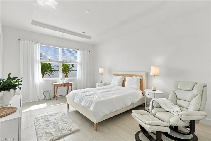 Recessed lighting, large window with water scenery, white window treatments, tiled flooring, and a ceiling soffit with integrated lighting