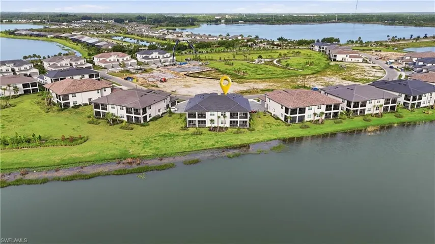 Waterfront property featuring multiple balconies, manicured green spaces, and a tile roof