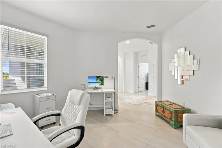 Arch top doorway, white walls, window with blinds, light-toned tile flooring
