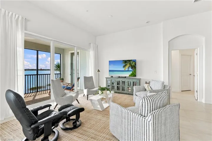 Expansive living area with large sliding glass doors, a screened balcony, and water views