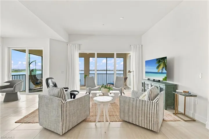 Bright living area with tile flooring and multiple sliding glass doors opening to a balcony