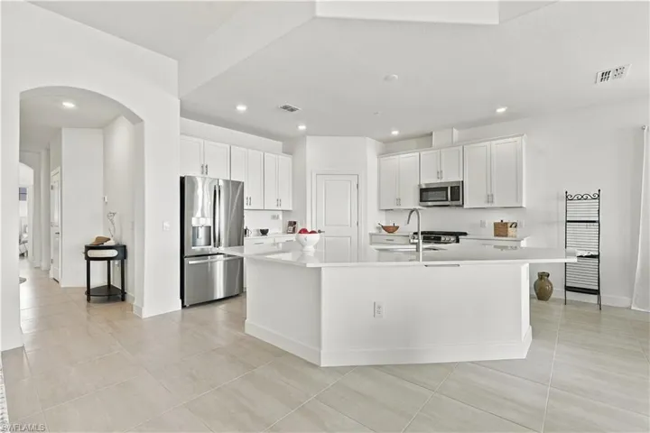 Open-concept kitchen with white cabinetry, stainless steel appliances, a central island, and recessed lighting