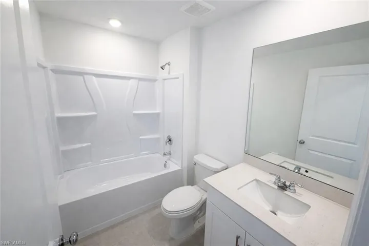 Bathroom featuring vanity, tub / shower combination, and light tile patterned floors