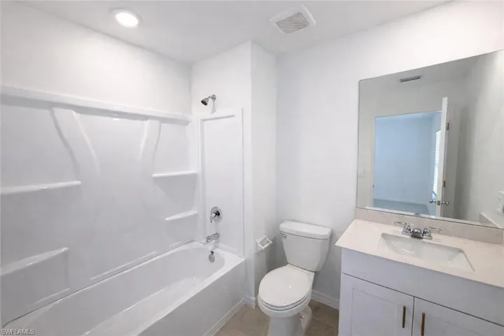 Full bath with vanity,  shower combination, and dark tile patterned flooring