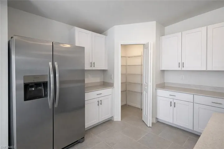 Kitchen featuring stainless steel fridge with ice dispenser, white cabinetry, and light tile patterned flooring