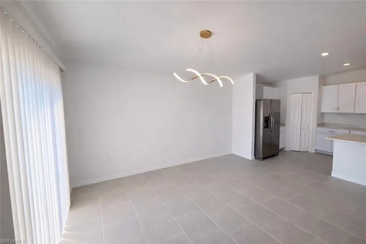 Kitchen featuring white cabinetry, stainless steel fridge with ice dispenser, suspended lighting, and open floor plan