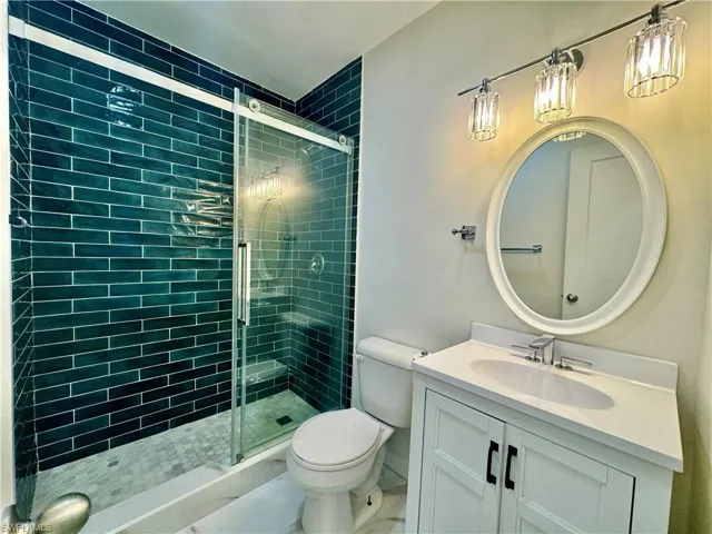 Bathroom with tile floors, an enclosed shower, oversized vanity, and toilet