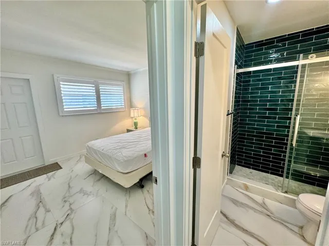 Bathroom with tile floors, a shower with door, ornamental molding, and toilet