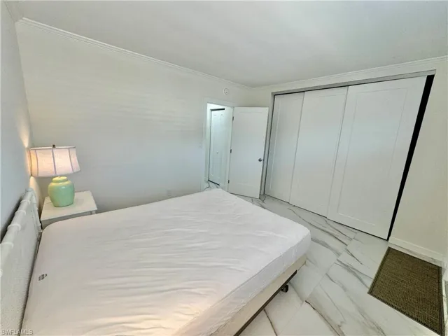 Bedroom featuring a closet, light tile flooring, and ornamental molding