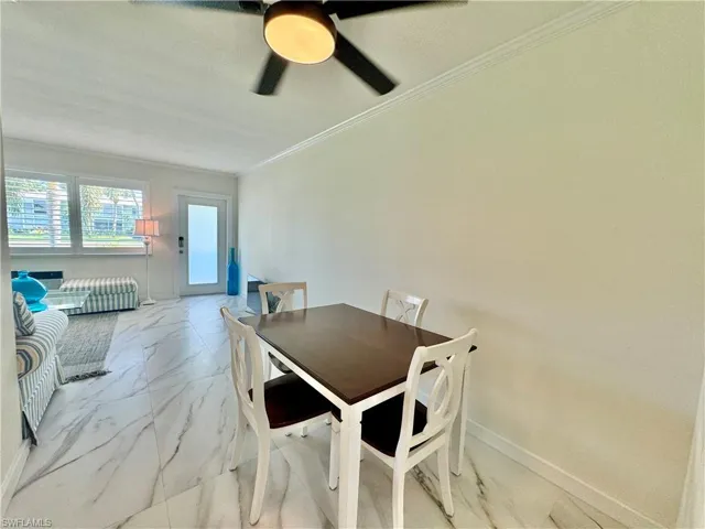 Dining area with ceiling fan, light tile flooring, and ornamental molding