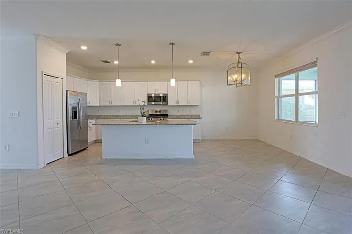 Kitchen with stainless steel appliances, white cabinetry, dark stone countertops, light tile patterned floors, and ornamental molding