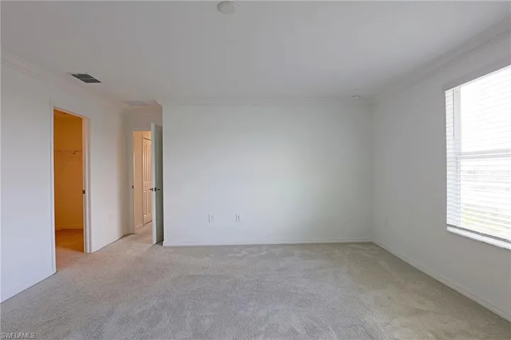 Spare room with crown molding and light carpet