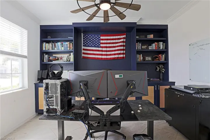 Home office with built in shelves, ceiling fan, crown molding, and light tile patterned floors