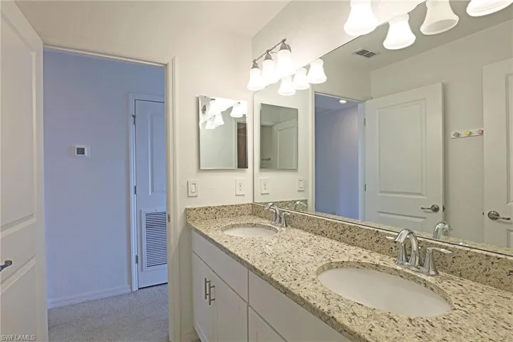 Full bathroom with double vanity and a textured wall