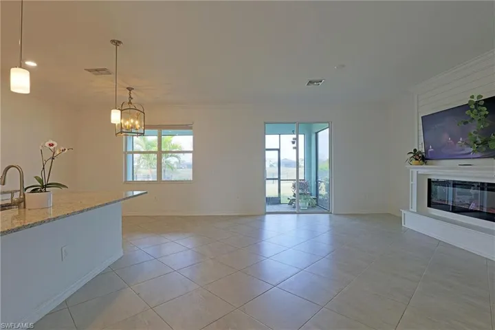 Unfurnished living room with a glass covered fireplace, light tile patterned flooring, suspended lighting, and crown molding