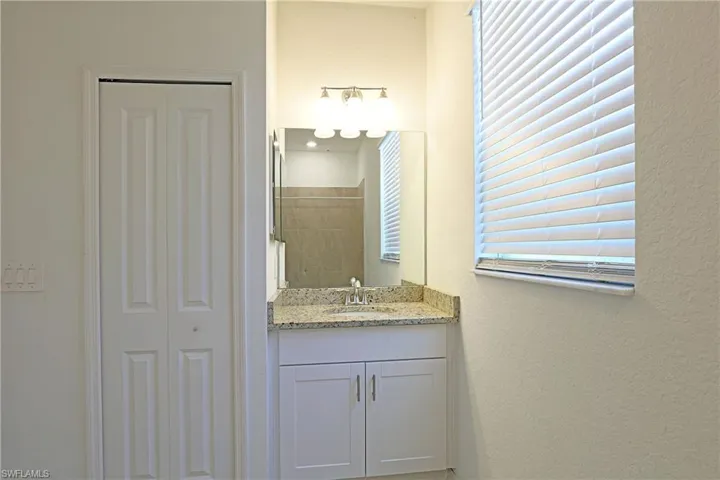 Full bath with vanity, a closet, a tile shower, and a textured wall