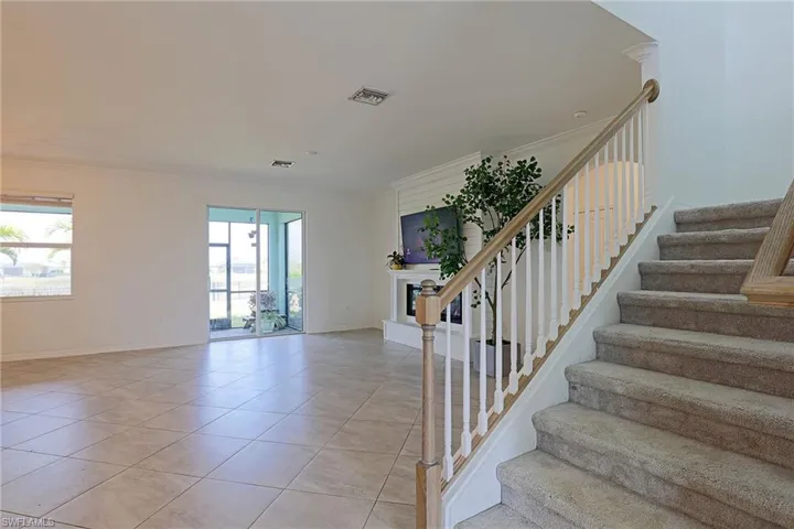 Stairs featuring ornamental molding, tile patterned flooring, and a fireplace with raised hearth