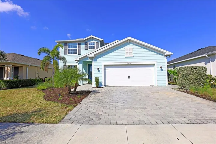 Traditional-style home with driveway, an attached garage, and a front yard