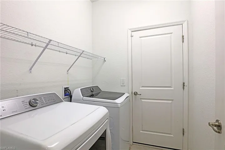 Laundry area with a textured wall and independent washer and dryer