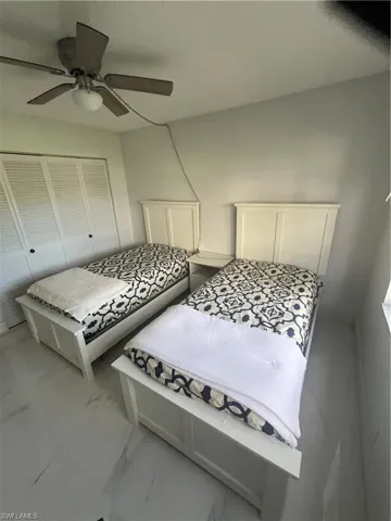 Bedroom with a ceiling fan, marble finish flooring, and a closet