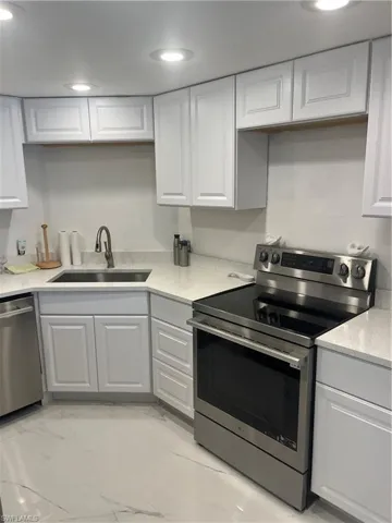 Kitchen with stainless steel range, dishwashing machine, light stone counters, white cabinets, and recessed lighting