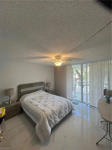 Bedroom featuring access to outside, ceiling fan, a textured ceiling, and expansive windows