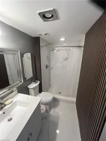Bathroom featuring vanity and a marble finish shower