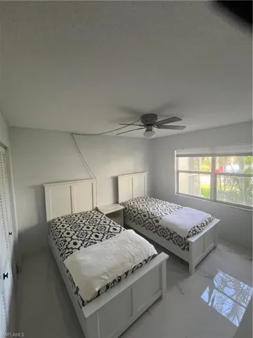 Bedroom with marble look tile flooring, a ceiling fan, and a closet