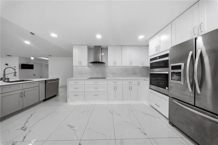Kitchen with stainless steel appliances, white cabinetry, recessed lighting, and light marble finish flooring