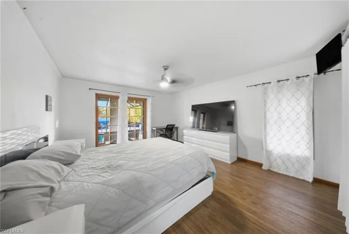 Bedroom featuring dark wood-type flooring, a ceiling fan, crown molding, and access to exterior