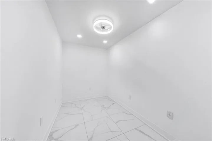 Empty room featuring light marble finish floors and recessed lighting