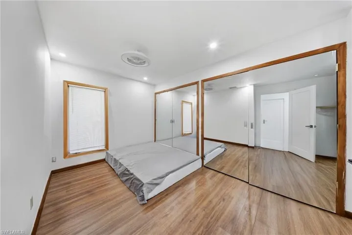 Unfurnished bedroom with wood finished floors, two closets, and recessed lighting