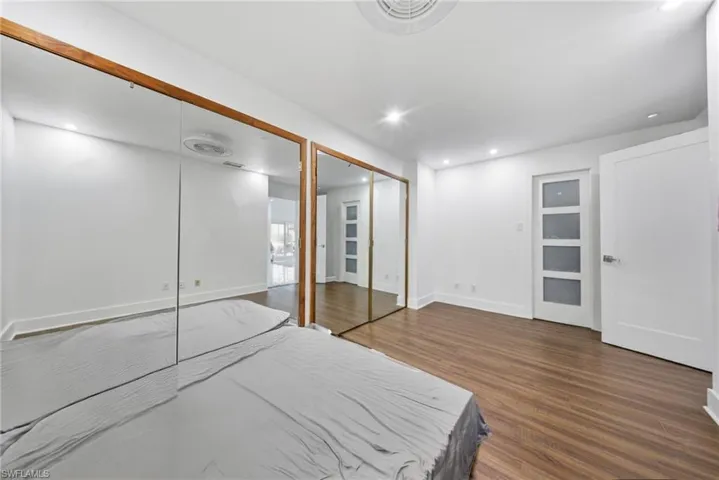 Bedroom with multiple closets, dark wood finished floors, and recessed lighting