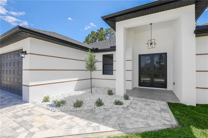 Doorway to property with a garage, french doors, stucco siding, and a shingled roof