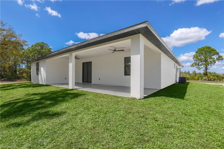 Rear view of house featuring a lawn, a patio, stucco siding, and a ceiling fan