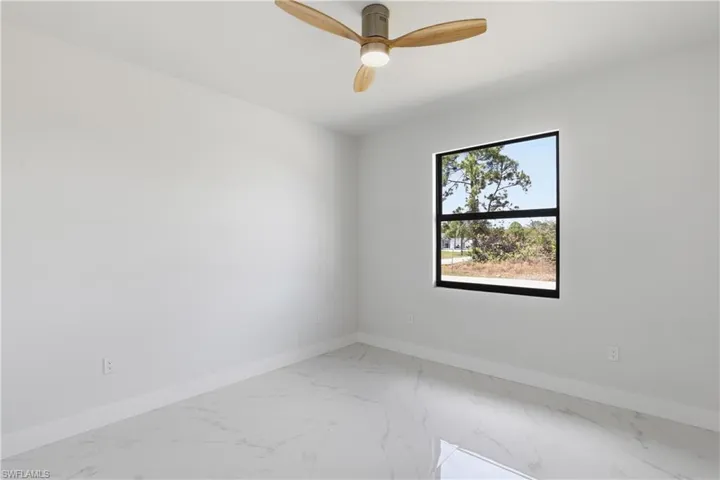Spare room featuring light marble finish flooring and a ceiling fan