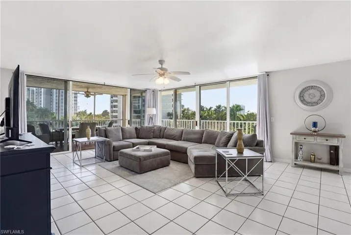 Living area with light tile patterned floors, a ceiling fan, and expansive windows