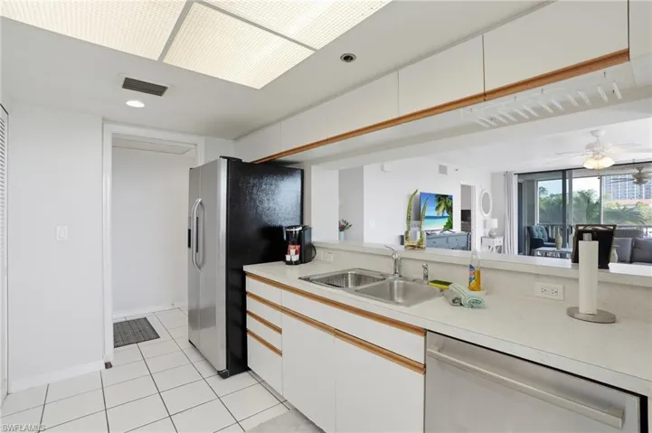 Kitchen featuring light countertops, two tone cabinets, stainless steel appliances, light tile patterned floors, and recessed lighting