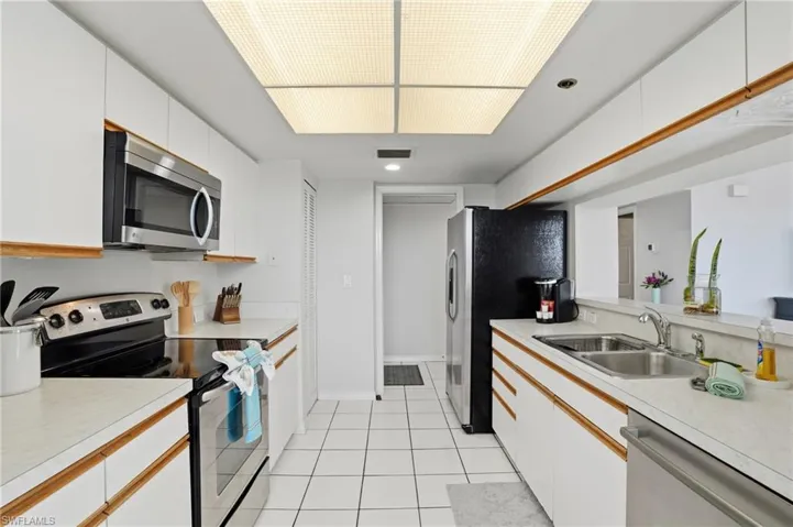 Kitchen with stainless steel appliances, light countertops, two tone cabinetry, light tile patterned floors, and recessed lighting