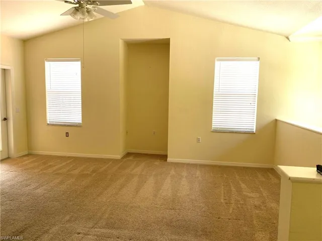 Spare room with light colored carpet, vaulted ceiling, and ceiling fan