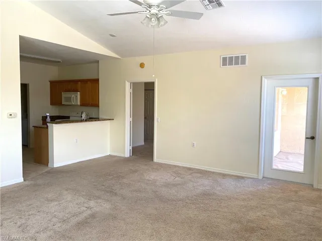 Unfurnished living room featuring light carpet, a ceiling fan, and lofted ceiling