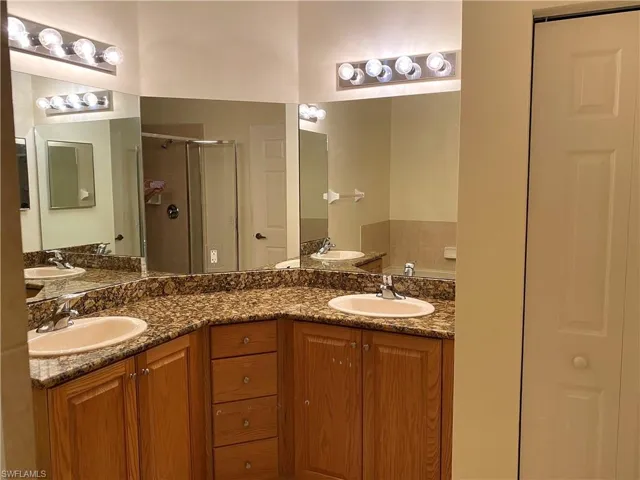 Bathroom featuring a shower stall, double vanity, and a closet