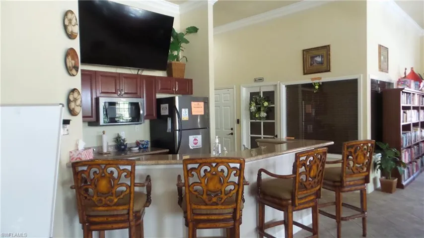 Kitchen with a kitchen breakfast bar, appliances with stainless steel finishes, dark stone counters, ornamental molding, and a peninsula